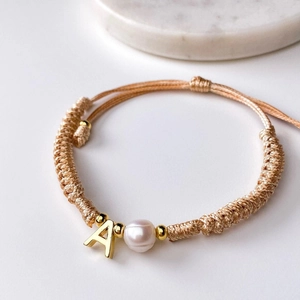 Detailed view of handmade woven cord bracelet with pearl and letter A charm