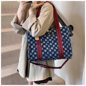 Detail of denim tote bag showing red and blue plaid pattern and reinforced webbing handles