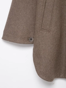 Detailed close-up of brown wool coat sleeve with button and textured pocket stitching