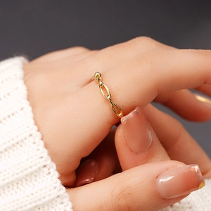 Gros plan d'une bague en maille dorée minimaliste portée sur un doigt avec un pull douillet