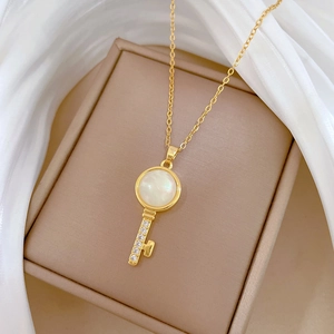 Elegant gold titanium key necklace with cat eye stone and diamonds on silk background