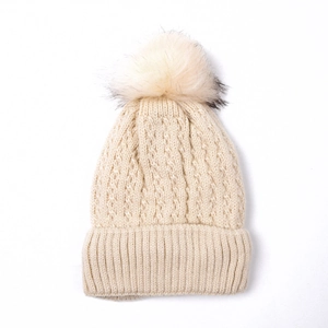 Close-up of beige cable knit beanie featuring a premium faux fur pompom and soft texture