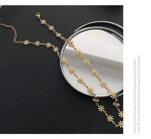 Close-up of golden daisy necklace with white enamel petals and adjustable lobster clasp