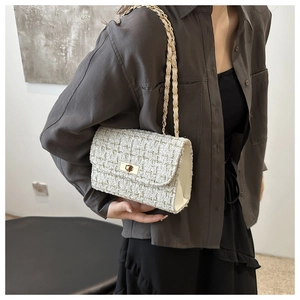 Detail view of tweed chain crossbody bag with metal twist lock and woven texture
