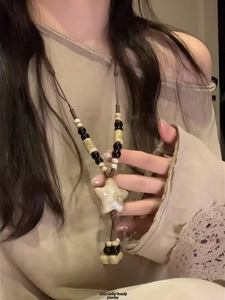 Detail of vintage beaded necklace featuring a beige star pendant and ethnic leather cord