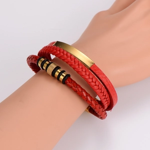 Detail of red braided leather bracelet with gold metal plates and magnetic buckle on wrist