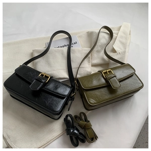 Detail view of wax leather shoulder bags in black and olive green with golden buckles