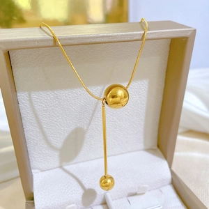 Close-up of gold snake chain necklace with round beads and metal bar in a jewelry box