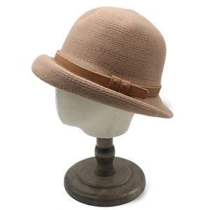 Detail of khaki knit cloche hat featuring a brown leather strap and golden rivets