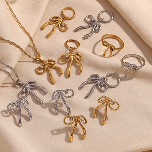 Elegant 18K gold and silver bow jewelry set with necklace, earrings and ring on satin
