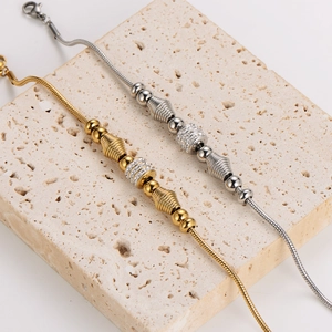Elegant gold and silver snake chain bracelets with sparkling rhinestones on stone background