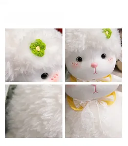 Close-up of white plush sheep toy with floral embroidery, lace bow, and soft texture