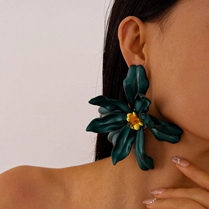 Close-up of model wearing oversized deep green acrylic flower earrings with yellow centers