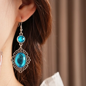 Close-up of vintage silver boho earrings with oval blue resin stones worn by model
