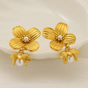 Elegant gold flower pearl earrings in a shell tray for a minimalist aesthetic