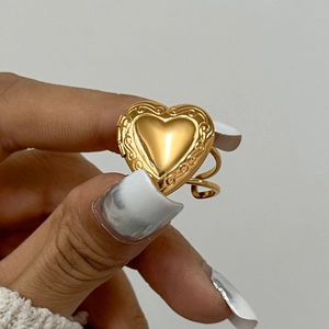 Detailed view of a gold heart-shaped locket ring with vintage textured borders