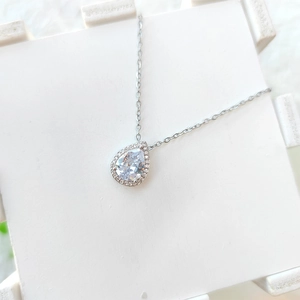 Macro detail of silver-tone teardrop pendant with sparkling pear-cut clear zircon stone