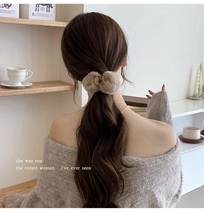 Detail view of a beige plush hair claw clip styled on a ponytail for autumn