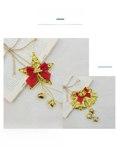 Close-up of golden Christmas bells and star ornaments with red bows on a vintage book.