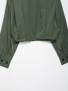 Detailansicht der dunkelgrünen Baseballjacke mit Plisseesaum und Schnallenbündchen