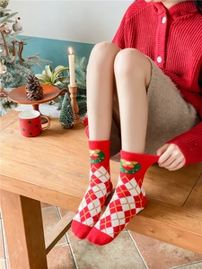 Detail of plush red Christmas plaid socks on person in cozy warm festive home setting