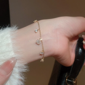 Close-up of a gold O-chain bracelet with five clear zircon charms on a model's wrist