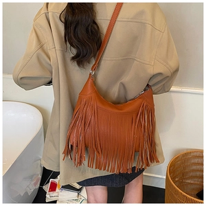 Close-up of brown leather shoulder bag with long tassels in a vintage bohemian style