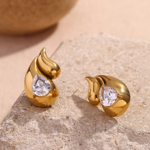 Macro detail of gold teardrop earrings with sparkling zircon stones on natural stone
