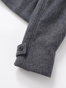 Detail of dark grey wool jacket cuff with black button and fine stitching texture