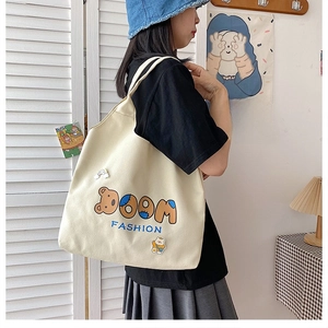 Nahaufnahme der cremefarbenen Canvas-Tasche mit BOOM FASHION Stickerei und Bären-Patches