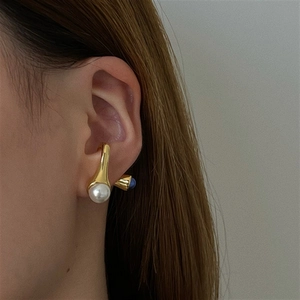 Elegantes pendientes dorados con piedra natural y perlas lucidos por una modelo