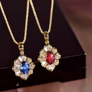 Makroaufnahme goldener Halsketten mit blauen und roten Zirkonia-Anhängern in Blumenform