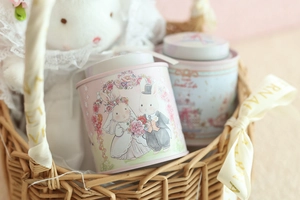 Mini bunny illustration tin boxes in pink and blue set in a decorative woven basket