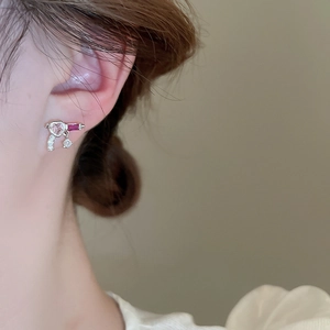Detailed view of silver heart earring with pink and red stones worn by model