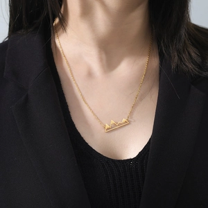 Golden mountain peak pendant necklace on model with black suit background for jewelry style