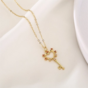 Gold key necklace with heart-shaped head and colorful zircon stones on white silk