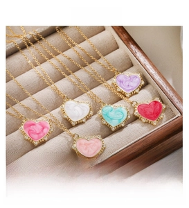 Detail view of colorful heart-shaped enamel pendants with gold accents on a jewelry tray