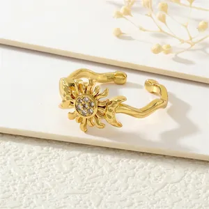 Close-up of wavy gold open ring featuring a zircon-studded sun and moon design