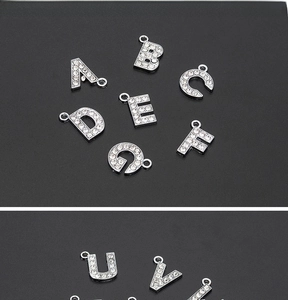 Detailed view of silver-tone rhinestone-encrusted alphabet charms on a dark background