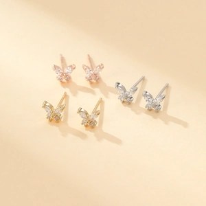 Detailed macro view of butterfly stud earrings in rose gold, gold and silver finishes