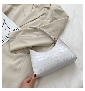 Close-up of white crocodile pattern faux leather shoulder bag with golden hardware detail