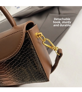 Detail of detachable gold metal hardware and brown crocodile texture leather on bag