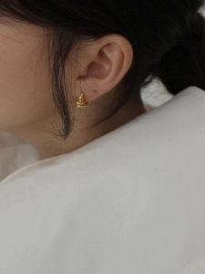 Close-up of golden spiral twisted hoop earring on model showing minimalist texture