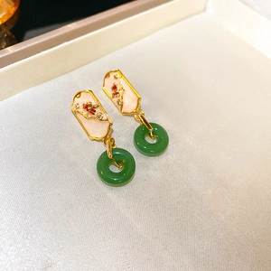 Detail view of gold-plated earrings with green jade-like ring and enamel inlay on fabric
