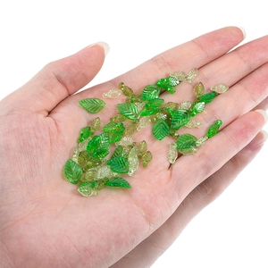 Green acrylic leaf charms for DIY jewelry making shown held in hand on white background