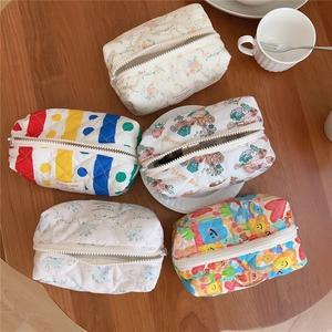 Quilted floral and bear pattern cotton cosmetic bags arranged on a wooden table