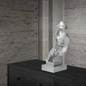 Modern silver Silence is Golden abstract face sculpture on a black pedestal stand