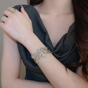 Dettaglio macro del bracciale rigido a fiore in argento e anello coordinato su modella