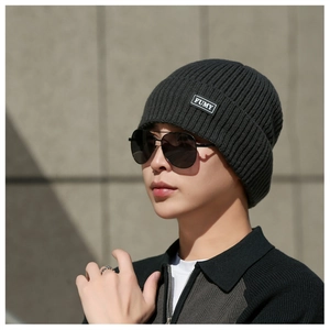 Detailed texture of thick dark grey ribbed knit beanie with white woven label patch
