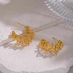 Artistic gold C-shaped earrings with irregular wire wrap design on a stone pedestal